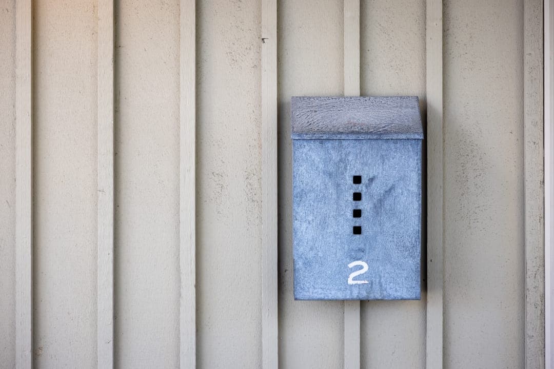 Une boîte aux lettres bleue sur un mur en bois.