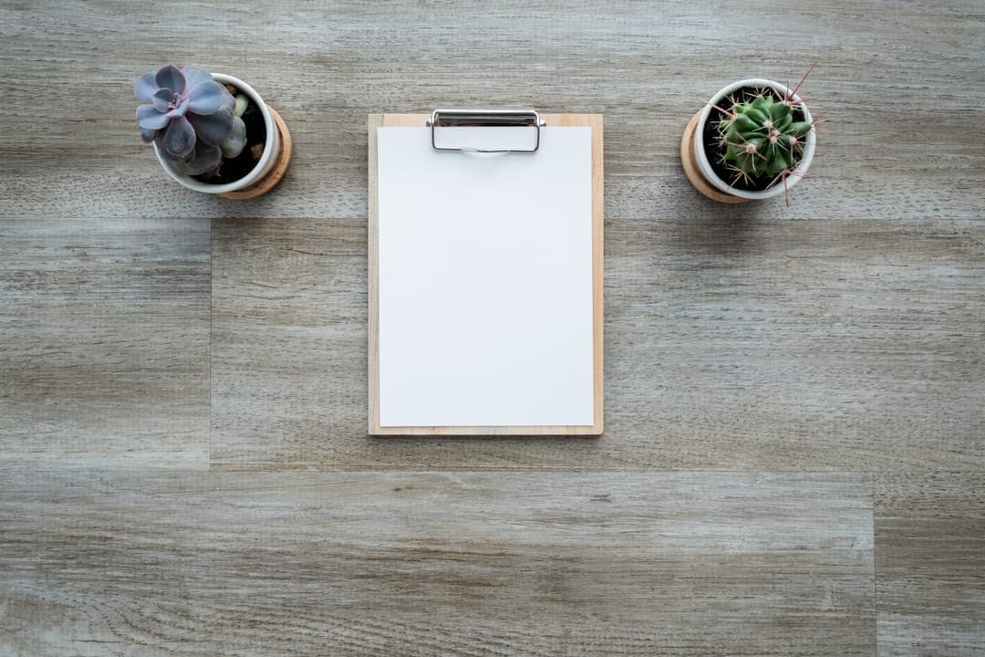 Un porte-bloc vierge sur une table en bois, entre deux plantes.