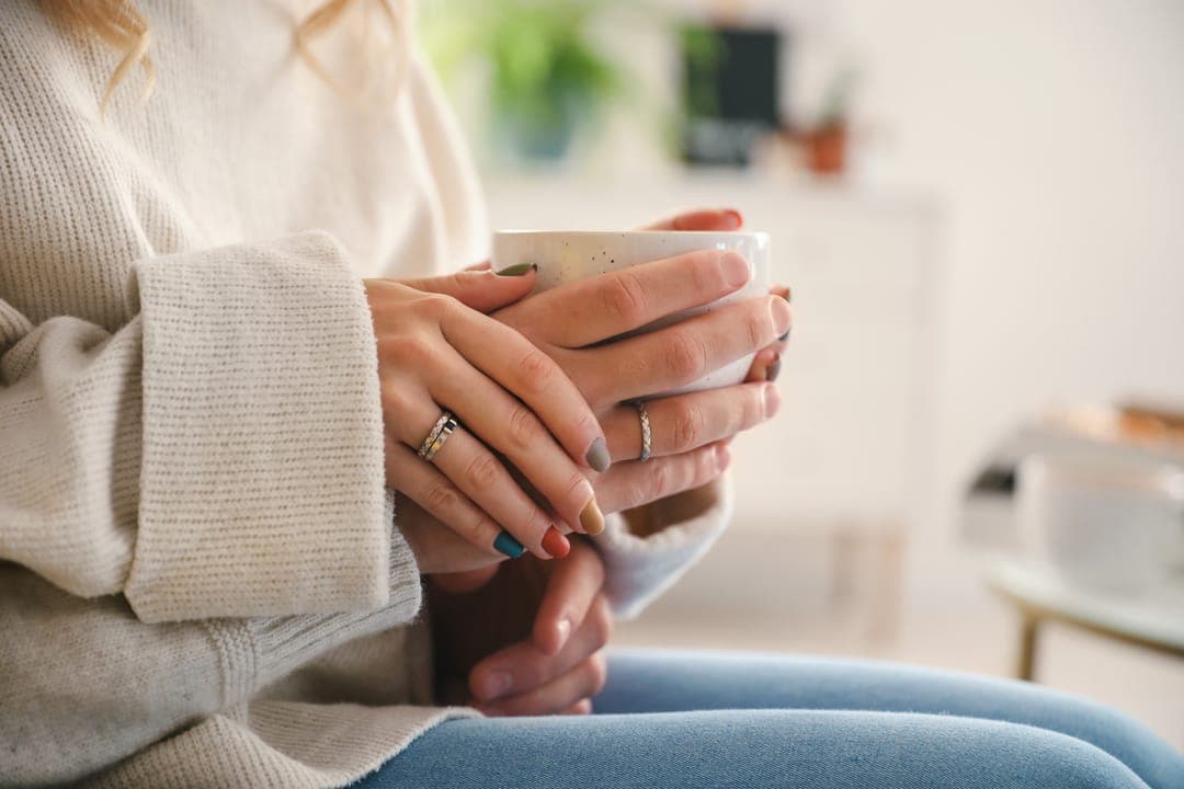 Les mains d'une personne âgée autour d'une tasse.