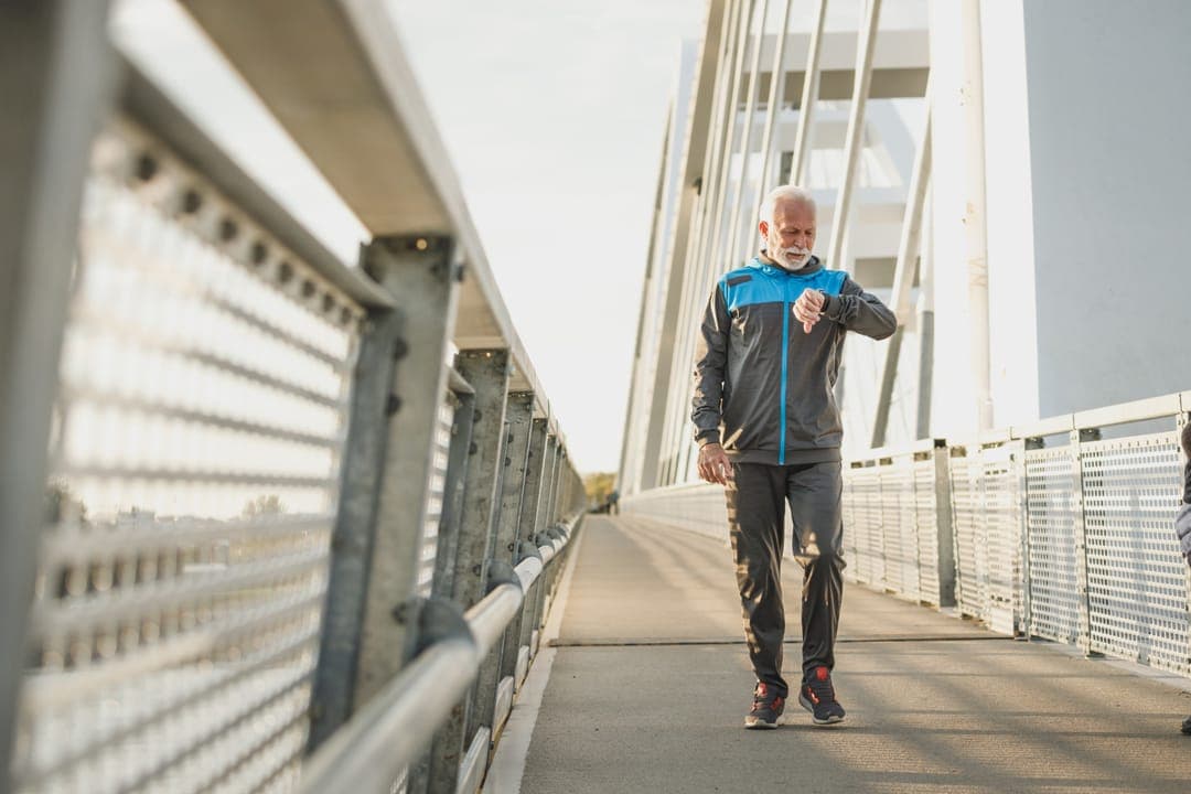 Un homme âgé marche seul sur une passerelle.